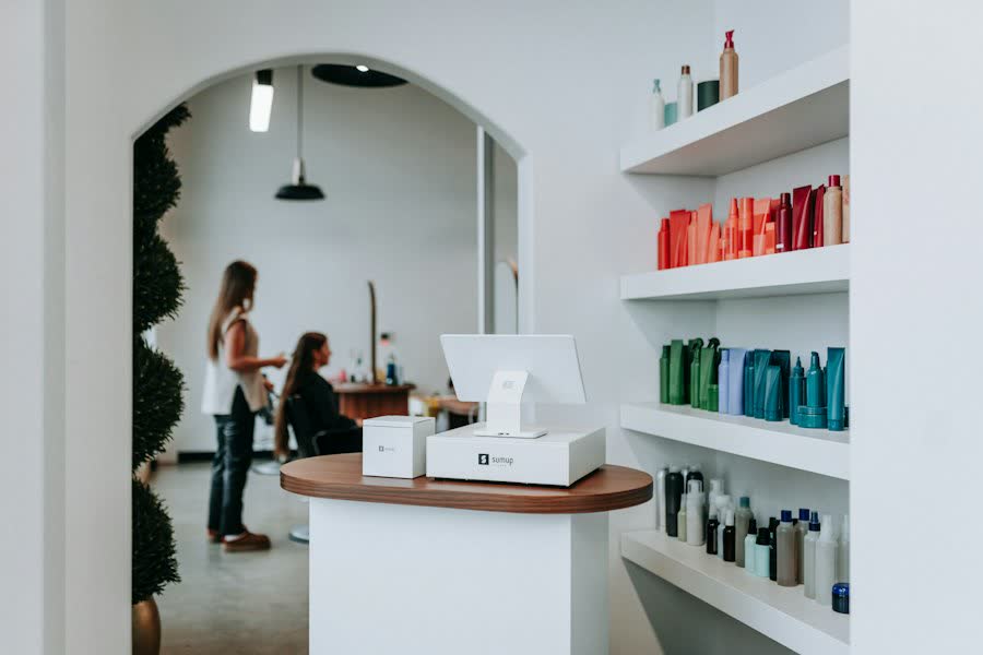 Heller Friseursalon mit Produktregal und Kundinnen.