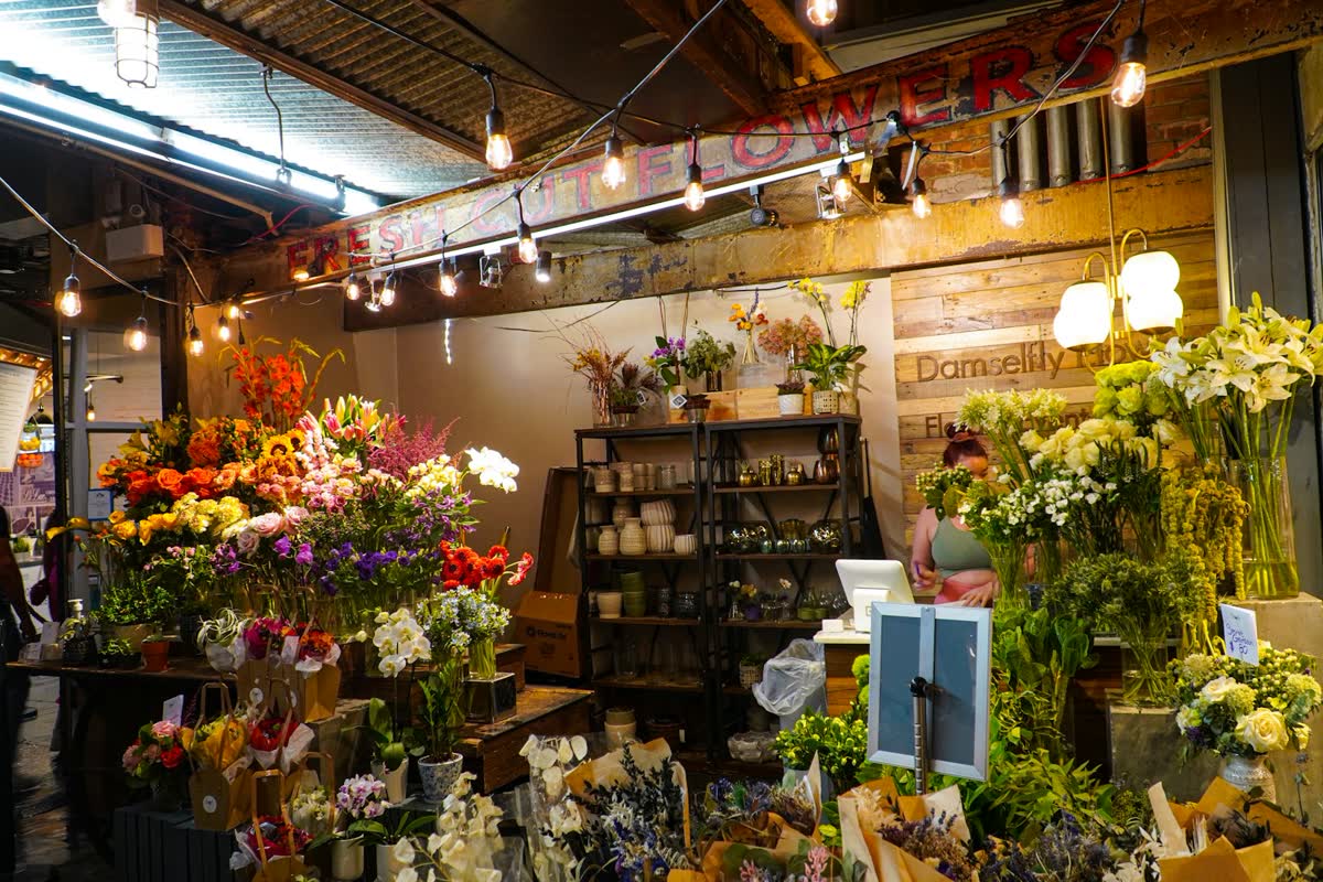 Blumenladen voller bunter Sträuße unter Lichterketten