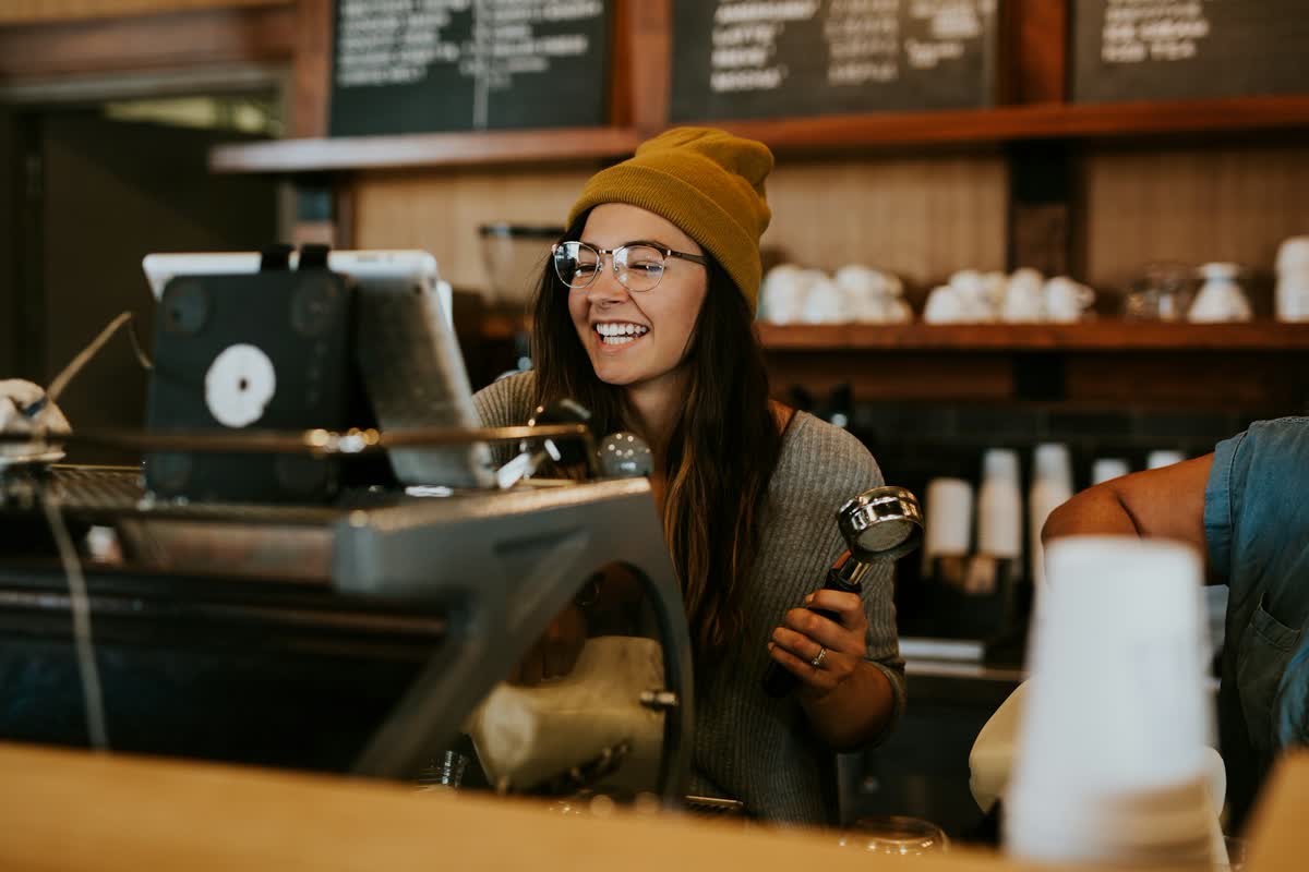 Barista mit Siebträger hinter dem Tresen eines Cafés