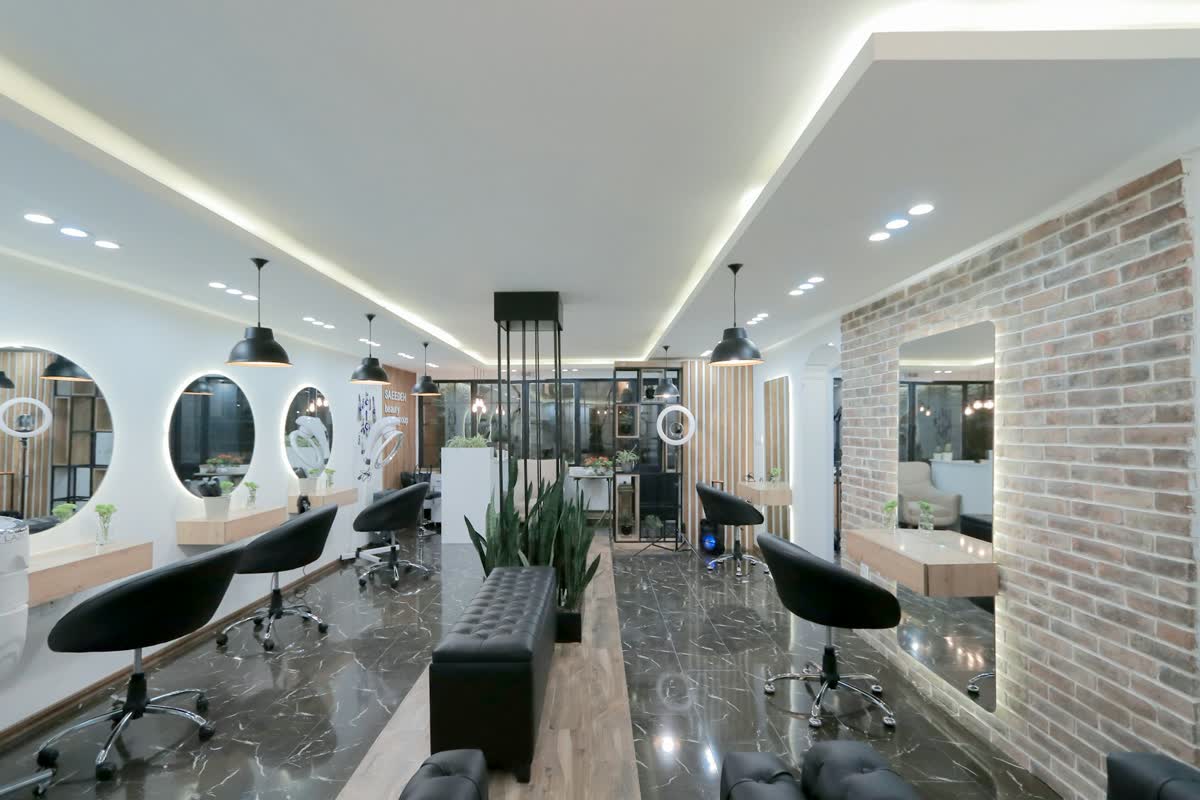 Heller Friseursalon mit runden Spiegeln und schwarzen Stühlen