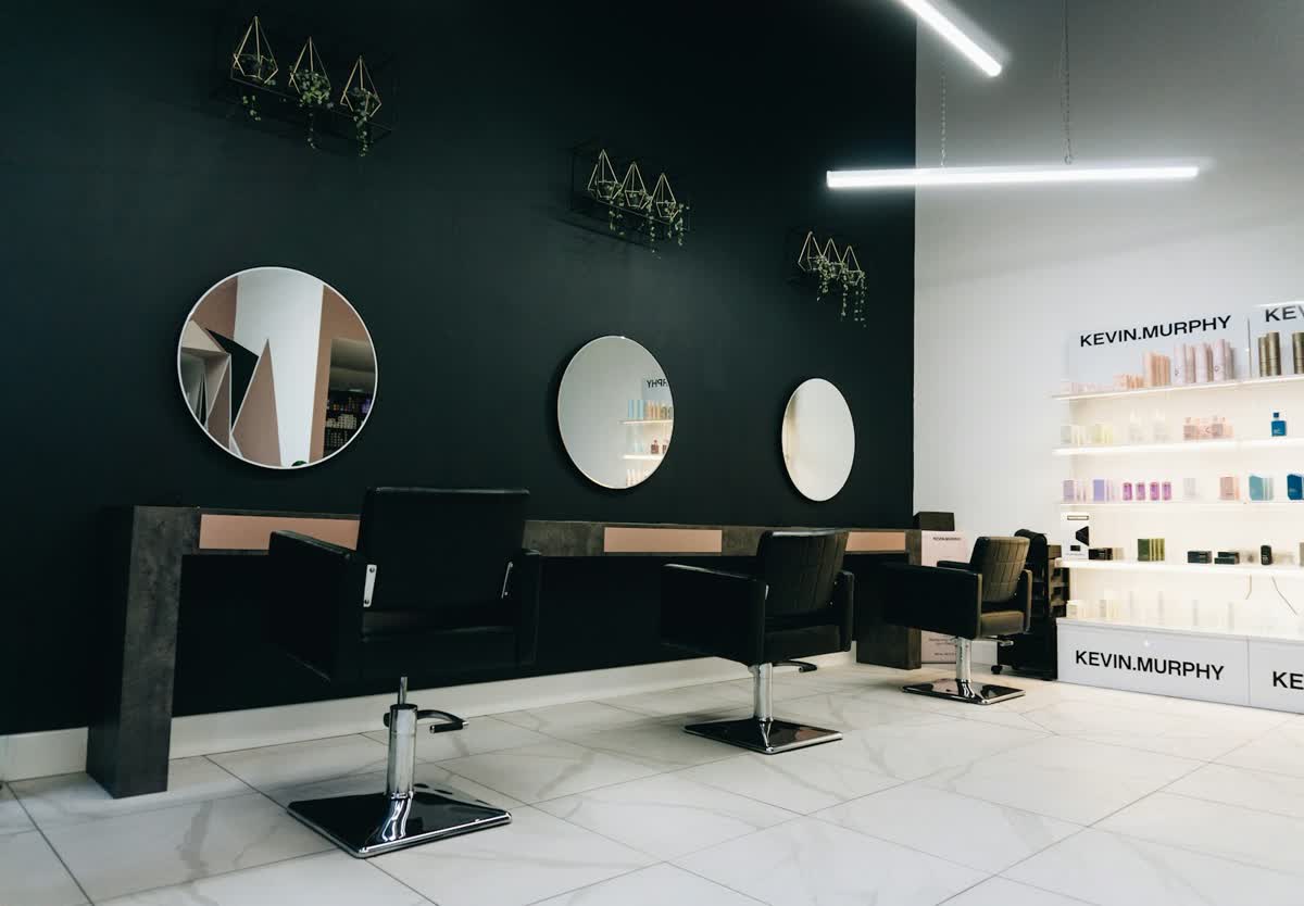 Drei Friseurstühle vor runden Spiegeln in einem Salon