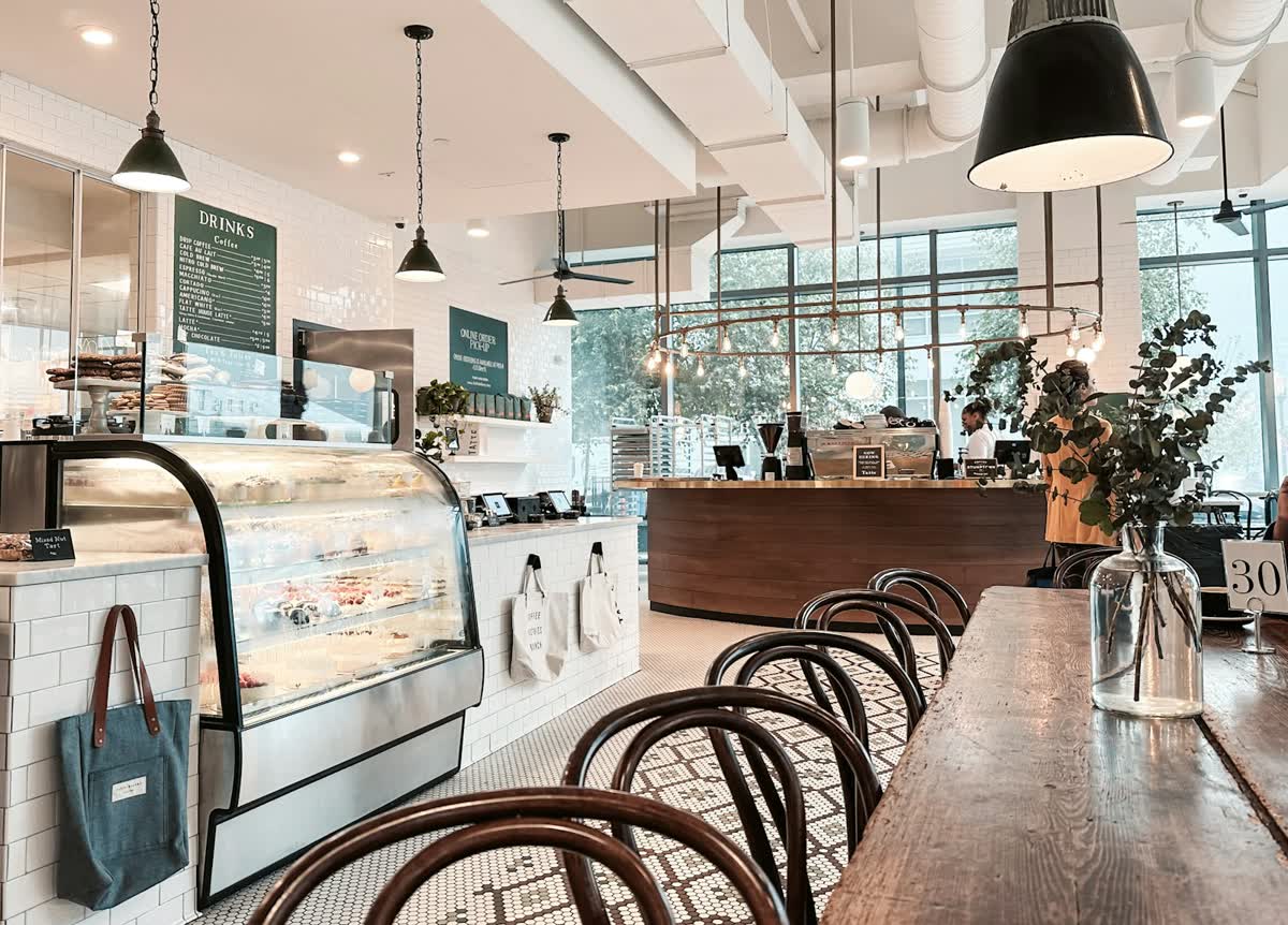 Helles Café mit Theke, Vitrine und Holztischen