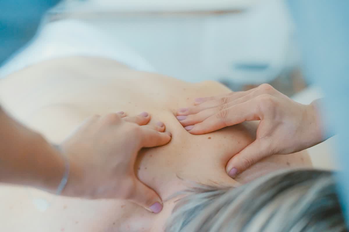 Hände eines Physiotherapeuten bei einer Rückenbehandlung