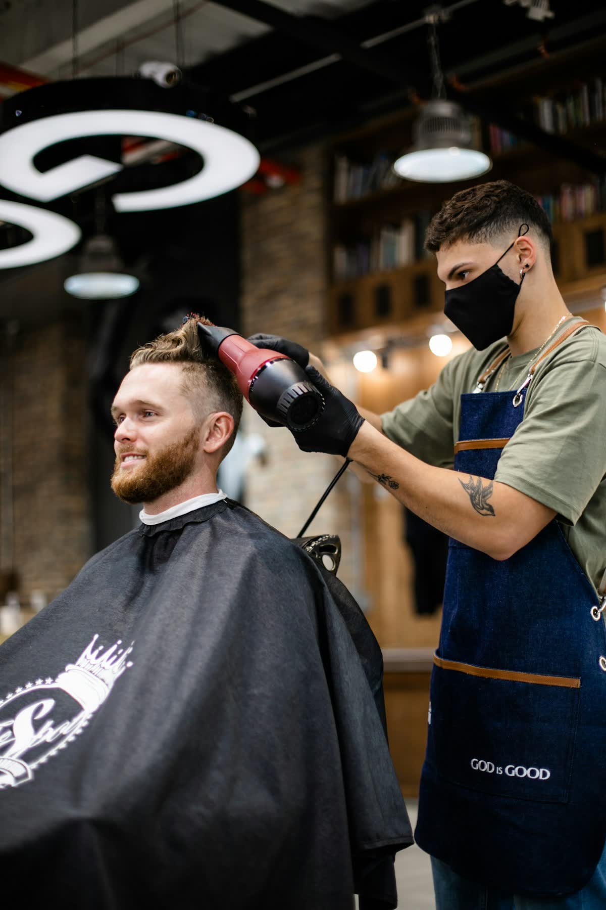 Friseur föhnt einem Kunden die Haare