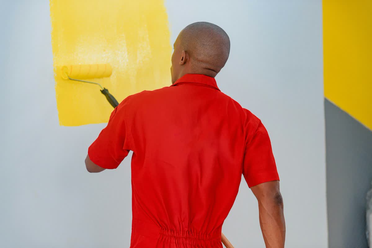 Maler streicht eine Wand mit gelber Farbe