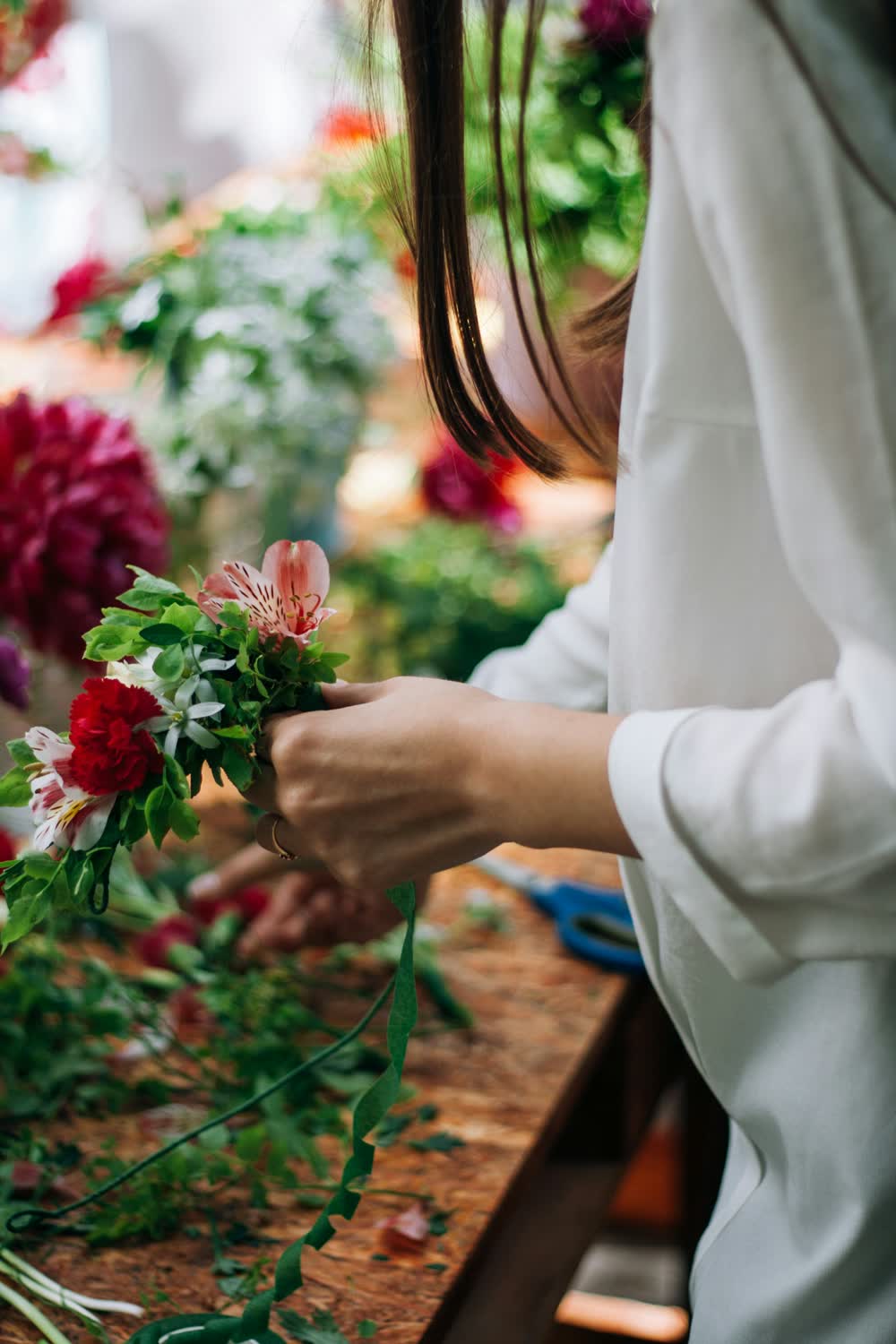 Floristin bindet einen Strauß aus roten und rosa Blumen.