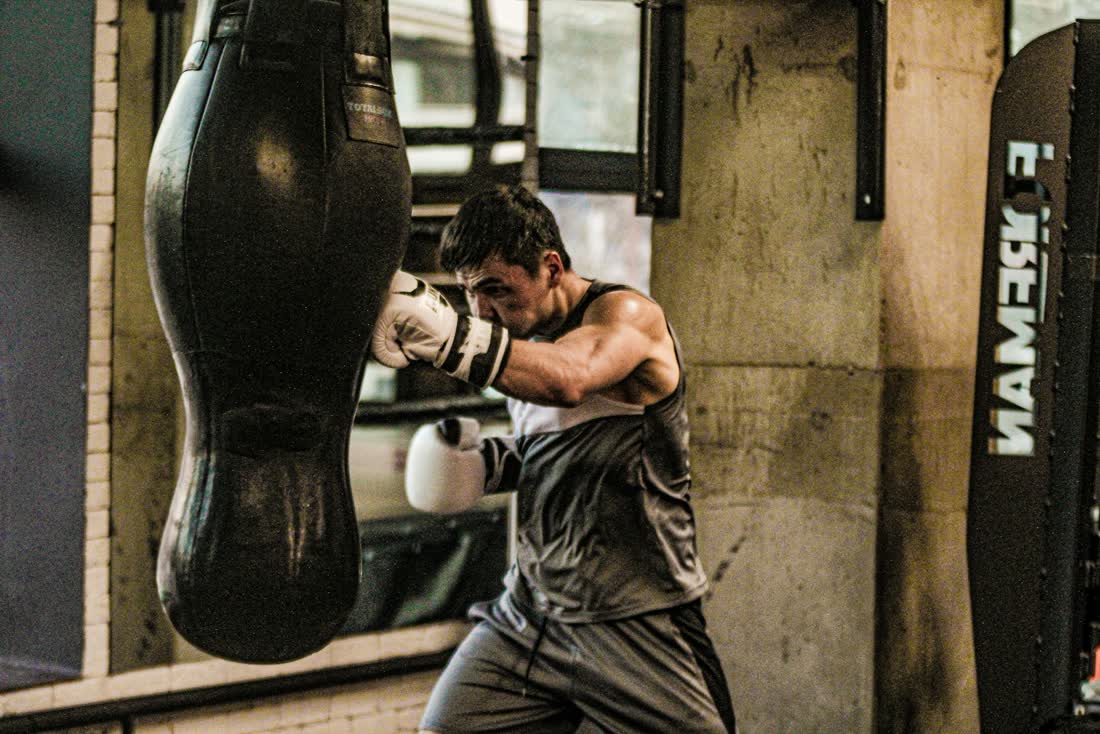 Ein Sportler trainiert am Boxsack in einem Studio.