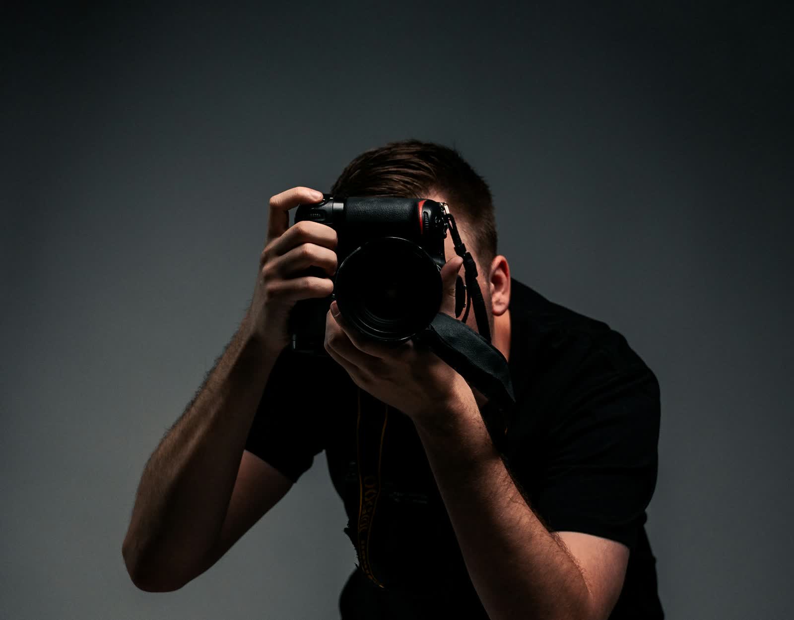 Ein Fotograf hält die Kamera vor das Gesicht und richtet sie auf das Motiv.