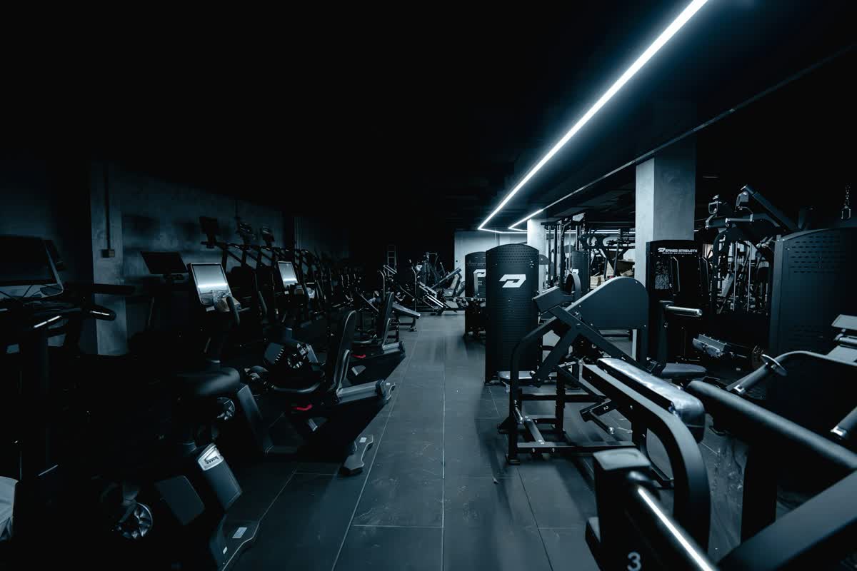Dunkles Fitnessstudio mit Geräten und Lichtleiste