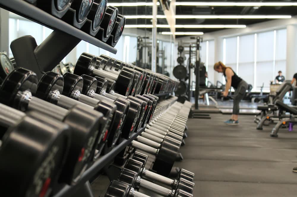 Fitnessstudio mit Hantelreihe im Vordergrund